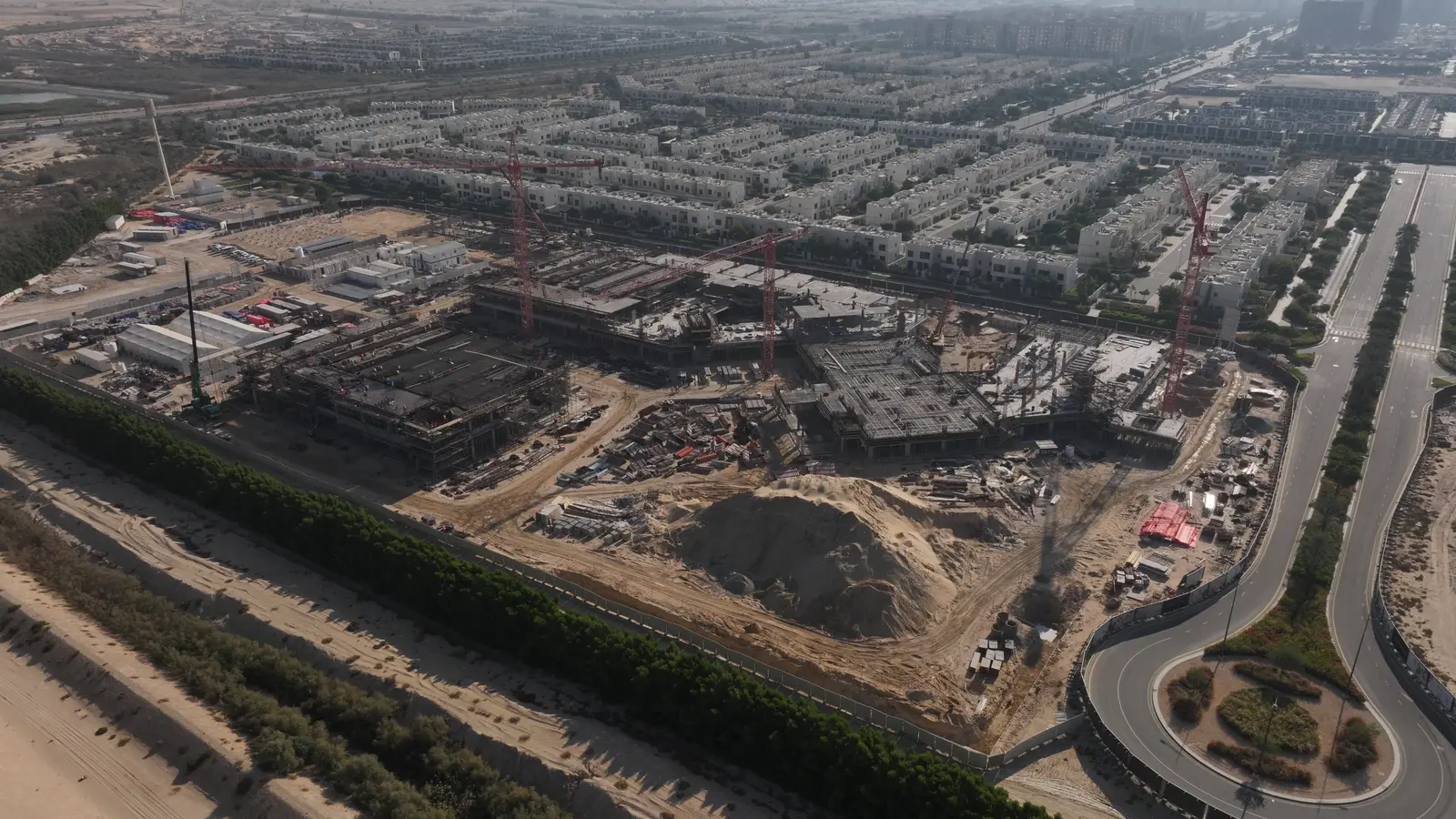 Aerial drone view over a UAE community showing tree belts, landscaped verges and irrigated planting